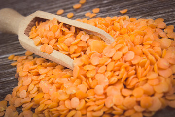 Vintage photo, Heap of red lentil with spoon on wooden background
