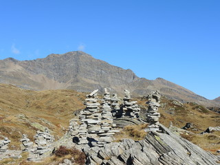 San Bernardino mountain pass, Switzerland. Fantastic landscape to the alpine mountains with blue sky. Rock cairns snd staked stones
