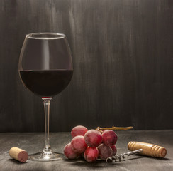Red wine, grapes, corkscrew, cork. Low-key photo