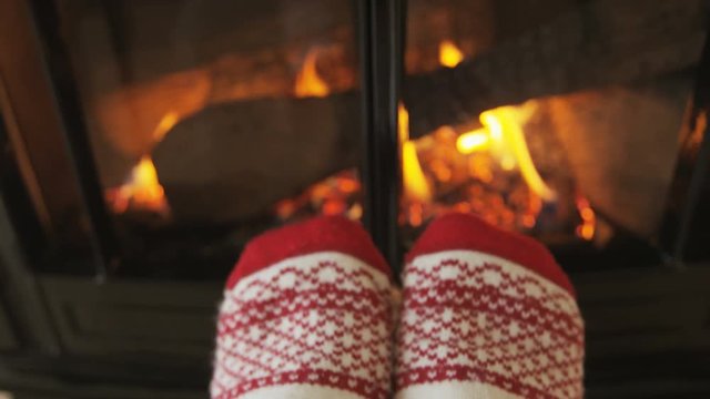 Woman drinking coffee by fireplace getting warm and cozy. Person is having refreshment during in living room. She is warming herself in front of burning stove during winter. RED EPIC SLOW MOTION.