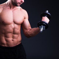 Fototapeta na wymiar close up of young handsome muscular man with dumbbells over grey