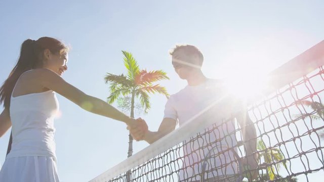 Tennis players handshake thanking each other for a game of tennis on court outdoor. Couple or mixed double tennis partners after playing tennis outside in summer. Happy young people, woman and man.