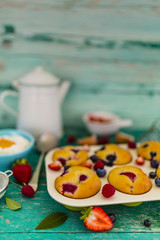 Delicious homemade pastries, muffins with berries on wooden table.
