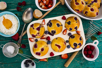 Delicious homemade pastries, muffins with berries on wooden table.