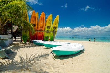 surface level shot,beautiful beach scenery, kayaks stack on white sandy beach at sunny day. clear sea water with cloudy clouds and blue sky.