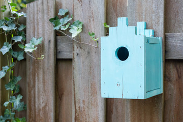 Blue birdhouse on a wooden fence