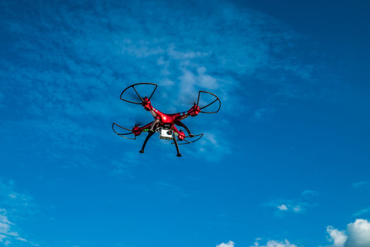 Roter Quadrocopter unter blauem Himmel fliegt durch die Luft