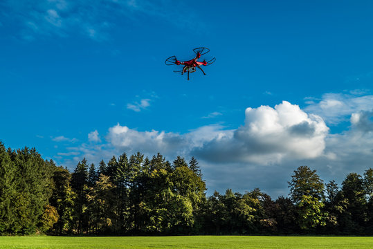 Rasanter Flug einer roten Drohne unter weiß-blauem Himmel