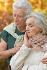 Sad elderly couple standing embracing outdoors