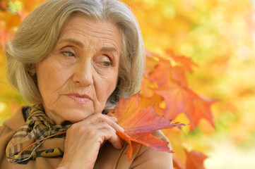 Sad elderly woman in autumn park