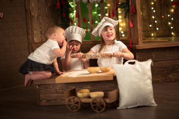 Obraz na płótnie Canvas Girls cook with a rolling pin to stretch dough, the concept of c