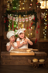 Fototapeta na wymiar Girls cook with a rolling pin to stretch dough, the concept of c