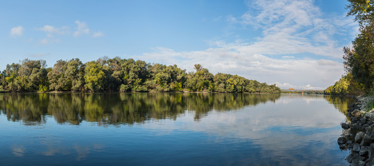 Early autumn landscape panorama with the river and a locomotive crossing the railway bridge .
