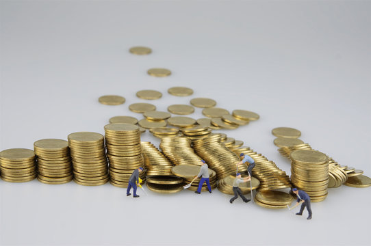 Miniature people are destroyed pile of gold coins