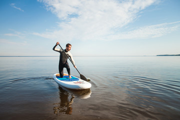 Young man paddling on sup board