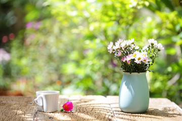 Flowers with vintage pot and heart shaped cup on wooden table
