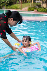 Asian Chinese Mom Teaching Little Girl Swimming At The Pool