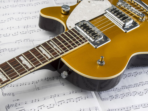 Guitarra electrica sobre una partitura de estudio con notas musicales 