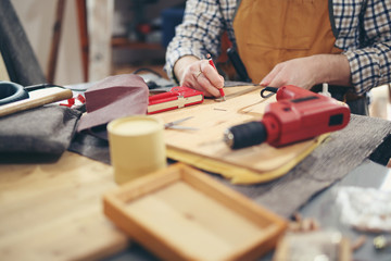 Man upholstering chair in his workshop, measure wooden board