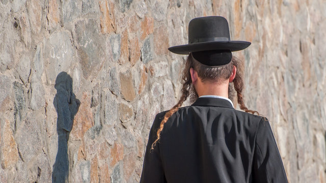Jew Hasid ethnic headdress. Human shadow on stone wall.