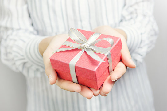 Closeup, Woman hand holding red gift box, female giving gift, New year holidays and greeting season concept