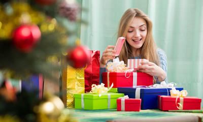 Fototapeta na wymiar Happy girl opening Christmas present and smiling