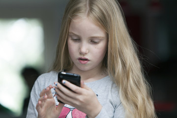 Fototapeta na wymiar young blond girl looks at mobile phone