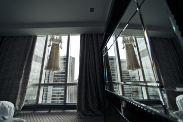 A view behind a mirror on a window with a wedding dress hanging