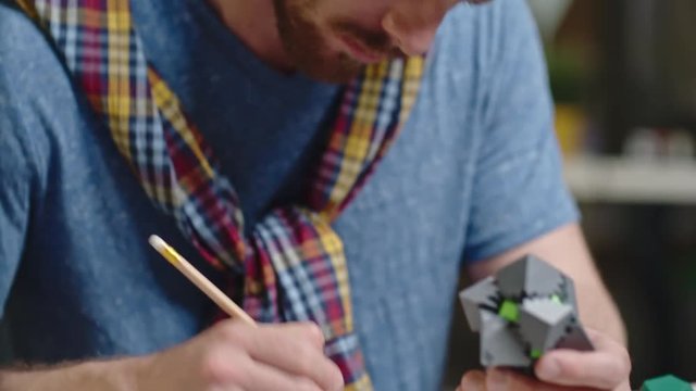 Tilt down of bearded engineer testing plastic puzzle game and making notes