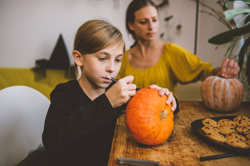 Daughter and mother creating Jack-O-Lantern