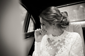 Pretty bride smiles sitting on the back seat in the car