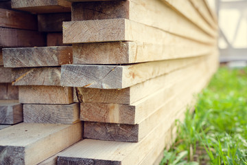 Stack of wooden bars. building material. Boards stacked on the green grass