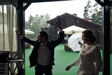 Fototapeta na wymiar Wet bride and groom walk into the restaurant pavilion