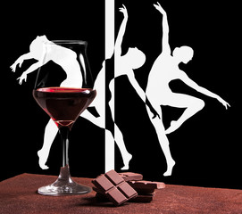Red wine glass with chocolate and graceful ballet dancers silhouette
