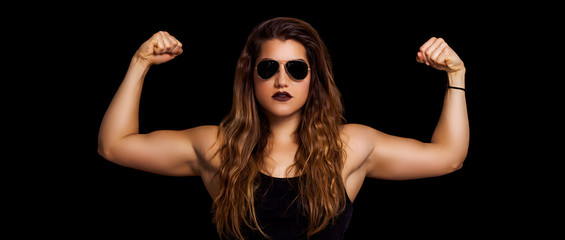 Female bodybuilder letterbox portrait showing muscles and wearing sunglasses