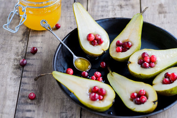 Fresh pears with cranberries and honey on a wooden rustic background