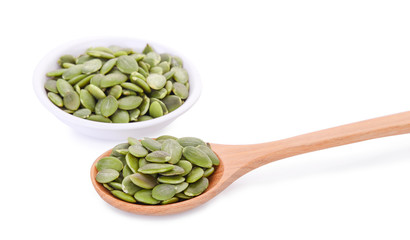pumpkin seeds in wooden spoon and white bowl  isolated on white