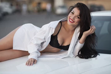Tuinposter Young sexy brunette woman in black lingerie and white shirt on sport car hood. © lashkhidzetim