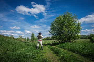 traveler in old clothes with a knapsack  on a country road