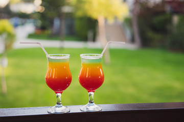Fresh alcoholic cocktails at resort bar. Colorful red, orange and green longdrinks with ice.
