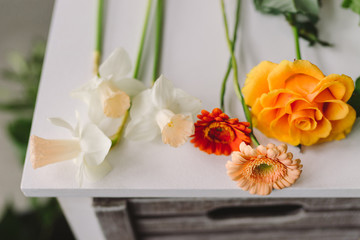Florist workspace closeup. Flowers and greenery on white wooden table.