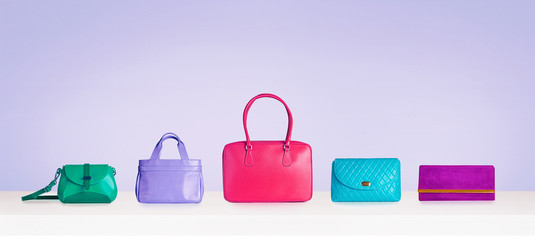 Colorful bag purse collection isolated on bright purple background. 