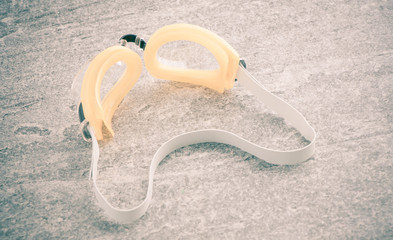Swimming goggles on stone surface. Rubber swim glasses used for protection under water. Sport...