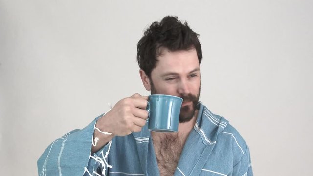 Model released man in studio enjoys a cup of coffee in the morning while still in his robe, 2 clip sequence.