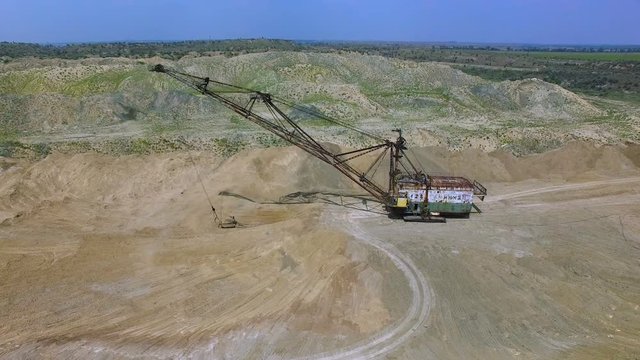 Flying over the excavator in a quarry. Production of manganese ore. aerial survey