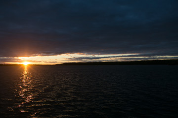 A sunset over a lake with yellow and pink through the clouds