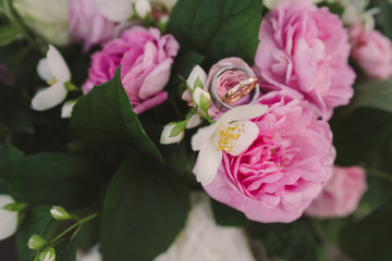 Beautiful bouquet of jasmine and pink garden roses with wedding rings on it, Shallow focus.