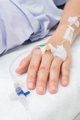 IV solution in a patient hand. Focus on asian woman's hand