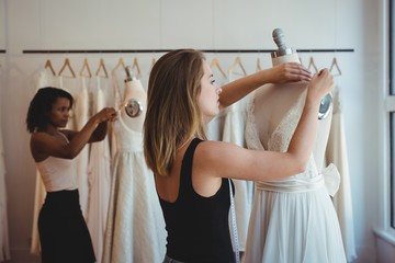 Female fashion designers adjusting the dress on mannequin