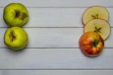 Whole and cut red and green ripe apples autumn harvest, from above on white wooden table